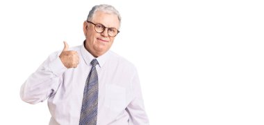 İş kıyafetleri giymiş yaşlı, kır saçlı bir adam mutlu bir el hareketi yapıyor. Kameraya bakıp başarıyı gösteren ifade. 