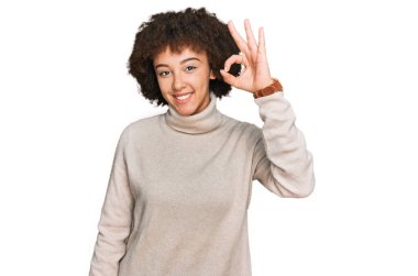 Kışın yün kazak giyen genç İspanyol kız gülümsüyor ve el ve parmaklarıyla 