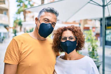 Coronavirus koruma maskesi takan orta yaşlı çift şehir caddesinde yürüyor..