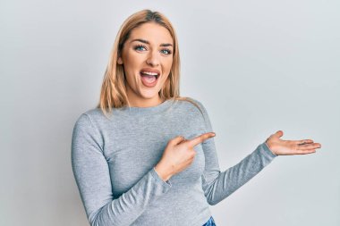 Gündelik giysiler giyen genç beyaz kadın kameraya hayret ediyor ve gülümsüyor.. 