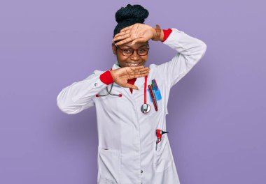 Genç Afro-Amerikan kadın doktor üniforması ve steteskop giymiş neşeli gülümseyen, elleri havada dikizleme oyunu oynayan. Şaşırdım ve çıktım. 