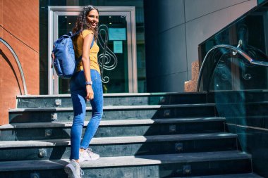 Genç Afro-Amerikan öğrenci gülümseyerek müzik akademisinin merdivenlerinden yukarı çıkıyor..