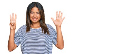 Gündelik giysiler giyen genç Latin kız sekiz numarayı gösterip işaret ederken kendinden emin ve mutlu gülümsüyor.. 