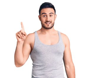 Mayolu ve kolsuz tişörtlü genç yakışıklı adam başarılı bir fikri işaret ediyor. Heyecanlı ve mutlu. Bir numara.. 