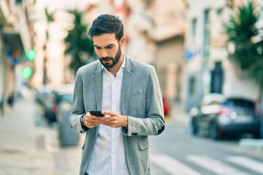 Şehirde akıllı telefon kullanan Latin asıllı genç bir işadamı..