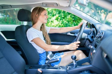 Genç, güzel, sarışın, gülümseyen mutlu araba kullanan kadın.