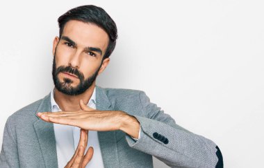 İş kıyafetleri giymiş genç İspanyol bir adam. El kol hareketleri yapıyor. Hayal kırıklığına uğramış ve ciddi bir yüz ifadesi takınıyor. 