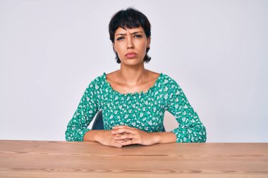 Güzel esmer kadın, gündelik giysiler giymiş, depresyonda ve endişe içinde, sinirli ve korkmuş bir şekilde masada oturuyor. hüzünlü ifade. 