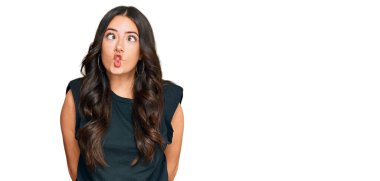 Siyah gömlekli güzel esmer bir kadın dudaklarıyla balık suratı yapıyor, çılgınca ve komik bir jest. Komik ifade. 