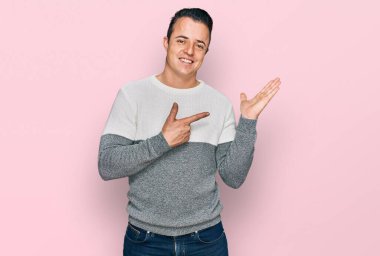 Kış süveteri giyen yakışıklı genç adam kameraya hayret ediyor ve gülümsüyor.. 