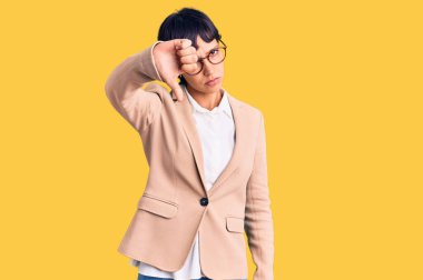 Kısa saçlı, iş ceketi giyen, gözlüklü, mutsuz görünen, reddedilmiş ve olumsuz jestli genç esmer kadın. kötü ifade. 