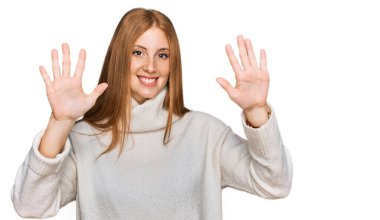 Kış süveteri giyen genç İrlandalı kadın on numarayı gösterip işaret ederken kendine güvenen ve mutlu bir şekilde gülümsüyor.. 