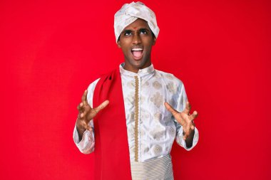 Geleneksel Sherwani elbisesi giyen yakışıklı Hintli adam deli gibi bağırıyor ve bağırıyor. Saldırgan bir ifade ve kollar havada. hüsran kavramı. 