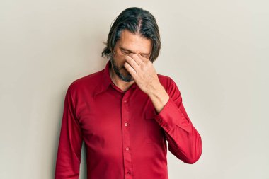 Orta yaşlı, sıradan kıyafetler giyen, burnu ve gözleri ovuşturup yorgun ve başı ağrıyan yakışıklı bir adam. Stres ve hüsran kavramı. 