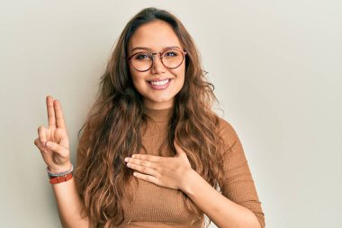 Gündelik kıyafetler ve gözlük takan genç İspanyol kız gülümsüyor. Göğsü ve parmakları havada küfür ediyor. Sadakat yemini ediyor. 