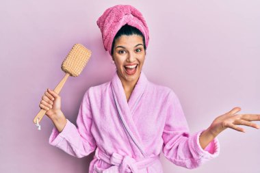 Duş bornozu giymiş, sünger tutan genç İspanyol kadın zaferi mutlu bir gülümsemeyle kutluyor ve kazanan yüz ifadesini kaldırıyor. 