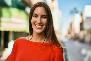 Genç İspanyol kadın gülümseyerek şehirde mutlu mesut dikiliyor..