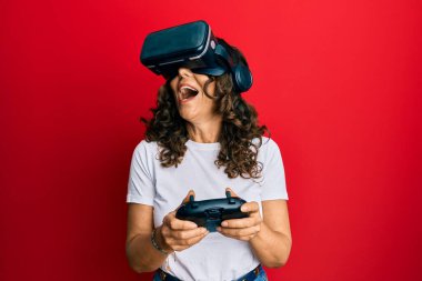 Sanal gerçeklik gözlüğü takan orta yaşlı bir kadın 3 boyutlu video oyunları oynuyor, gelecekteki simülasyonları izliyor, heyecan verici deneyimler yaşıyor.