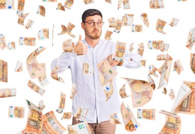 Zarif iş gömleği ve gözlük takan yakışıklı genç adam baş parmak kaldırıyor, anlaşmazlık ve anlaşma ifadesi takınıyor. çılgın çatışma