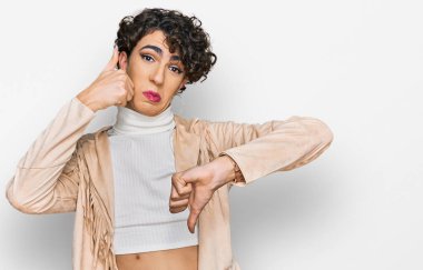 Makyaj yapan yakışıklı bir adam, kadın kıyafetleri, baş parmak hareketi, anlaşmazlık ve anlaşma ifadesi. çılgın çatışma 