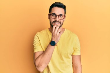 Günlük kıyafetler ve gözlük takan genç İspanyol adam kameraya kendinden emin bakıyor kollarını kavuşturmuş ve çenesini kaldırmış bir şekilde gülümsüyor. Olumlu düşünmek. 