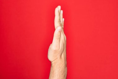 Kafkasyalı bir gencin elleri izole edilmiş kırmızı arka planda parmaklarını gösteriyor. Uzanmış el hareketlerini gösteriyor, itiyor ve duruyor.
