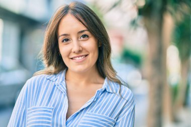 Genç İspanyol kadın gülümseyerek şehirde mutlu mesut dikiliyor..