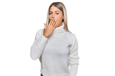 Balıkçı yaka kazak giyen güzel sarışın kadın ağzıyla ağzını kapatmaktan sıkılmış. Huzursuz ve uykulu.. 