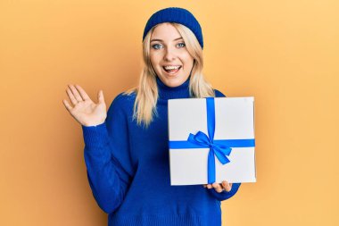 Beyaz bir kadın elinde hediyeyle zaferi mutlu bir gülümseme ve kazanan bir ifadeyle kutluyor. 