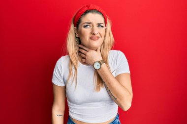 Beyaz günlük tişört giyen, boynu ağrıyan, boğazı ağrıyan, grip, mantar ve enfeksiyon kapmış genç beyaz bir kadın. 