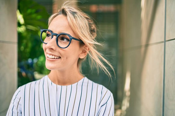 Молодая блондинка-бизнесмен улыбается счастливой прогулке по городу.