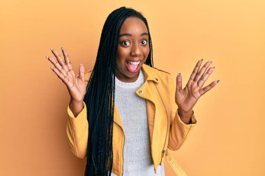 Genç Afro-Amerikalı kadın sıradan bir ceket giyip çılgınlığı kutluyor ve başarıya hayret ediyor kolları açık ve gözleri açık heyecanla haykırıyor. Kazanan konsept 