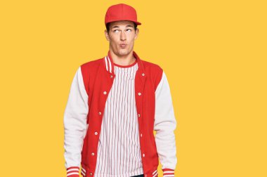 Beyzbol üniforması giyen yakışıklı beyaz adam dudaklarıyla balık suratı yapıyor, çılgınca ve komik bir jest. Komik ifade. 