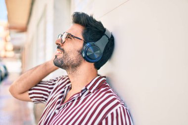 Sakallı, neşeli, kulaklık takmış, müzik dinleyen yakışıklı İspanyol bir adam.