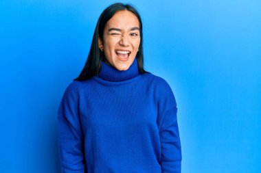 Sıradan bir kazak giyen genç Asyalı kadın kameraya seksi bir ifadeyle bakıyor, neşeli ve mutlu bir yüzle.. 