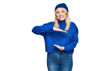 Kışın yün kazak giyen, büyük ve büyük beden işareti gösteren el kol hareketleri yapan beyaz bir kadın. Ölçü sembolü. Kameraya bakıp gülümsüyor. ölçüm kavramı. 