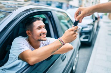 Yeni arabanın anahtarını tutarken mutlu gülümseyen İspanyol genç adam.