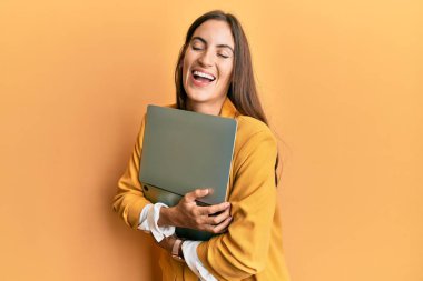 Genç, güzel bir kadın dizüstü bilgisayarını tutuyor ve kahkahalarla gülüyor.. 