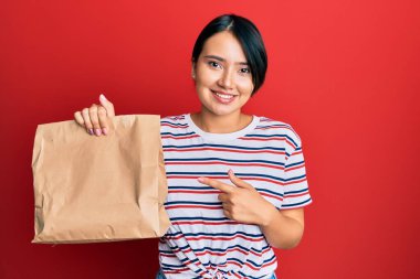 Kısa saçlı, güzel bir kadın. Paket çantasından alıp götürüyor. Gülümsüyor, mutlu bir şekilde işaret ediyor. 