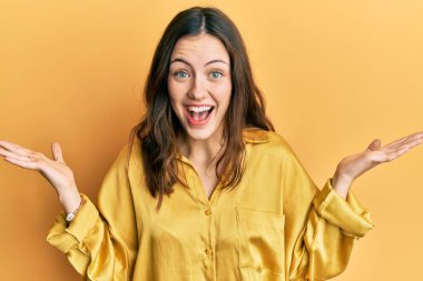 Genç esmer kadın gündelik sarı gömlekli mutlu bir gülümsemeyle zaferi kutluyor ve kazanan el kaldırıyor. 