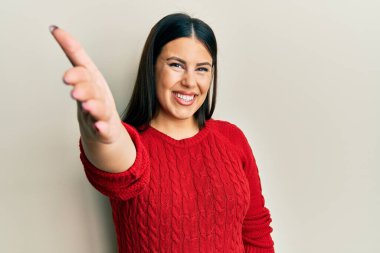 Yün kazak giyen güzel esmer kadın selamlama ve hoş geldin demek için dostça tokalaşıyor. başarılı iş. 