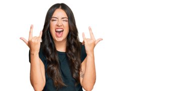 Siyah gömlekli, çılgın bir ifadeyle bağıran güzel esmer kadın elleri havada rock sembolü yapıyor. Müzik yıldızı. ağır kavram. 