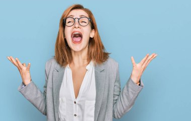 İş stili giyinmiş, gözlüklü, deli deli deli bağıran, agresif ifade ve kollarıyla bağıran beyaz bir kadın. hüsran kavramı. 