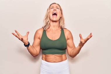 Orta yaşlı beyaz kadın spor kıyafetleri giyiyor deli gibi bağırıyor, bağırıyor, agresif bir ifade ve kollarla bağırıyor. hüsran kavramı. 