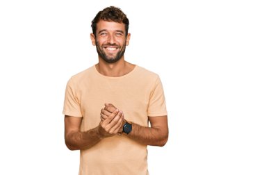 Sakallı, sıradan tişörtlü, elleri çapraz parmaklı, rahat ve neşeli gülümseyen yakışıklı bir genç. Başarı ve iyimserlik 