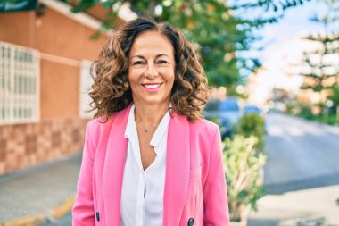 Orta yaşlı İspanyol iş kadını şehirde mutlu bir şekilde ayakta duruyor..