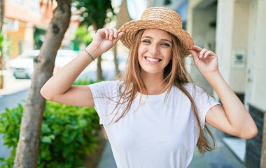 Genç sarışın kadın tatilde gülümsüyor. Mutlu bir şekilde caddede yürüyor.