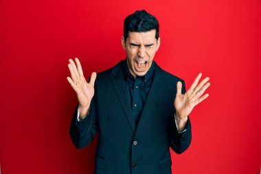 İş kıyafetleri giymiş yakışıklı İspanyol bir adam başarı için deli ve çılgınlığı kutluyor kollarını kaldırmış ve gözlerini kapatmış heyecanla bağırıyor. Kazanan konsept 