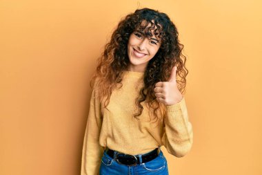 Gündelik kıyafetler giyen genç İspanyol kız elleriyle mutlu bir jest yapıyor. Kameraya bakıp başarıyı gösteren ifade. 