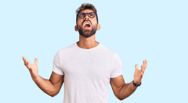 Gündelik kıyafetler giyen, gözlüklü, deli gibi bağıran, sinirli ifadeli ve kollarını kaldırmış genç İspanyol bir adam. hüsran kavramı. 